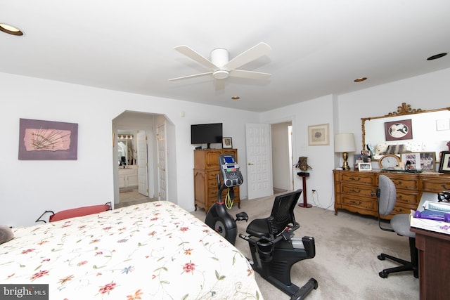 bedroom with light carpet, arched walkways, ensuite bath, and ceiling fan