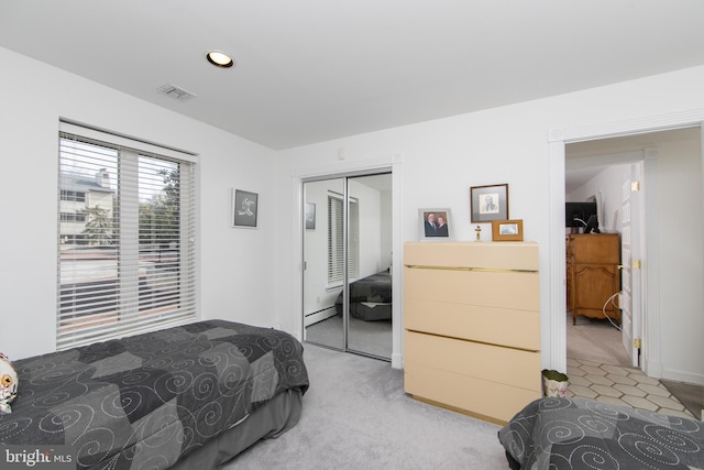 bedroom with visible vents, light carpet, a baseboard heating unit, recessed lighting, and a closet