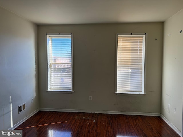 empty room with visible vents, baseboards, and hardwood / wood-style flooring