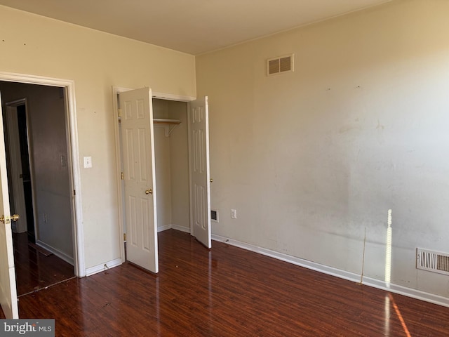 unfurnished bedroom featuring wood finished floors, visible vents, a closet, and baseboards