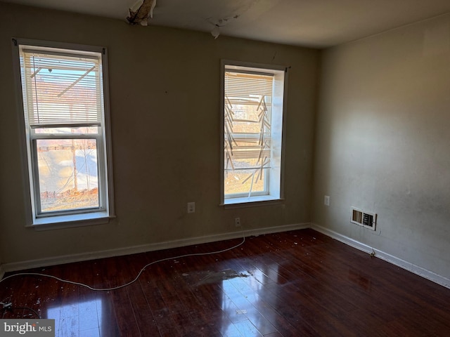 unfurnished room with visible vents, baseboards, and wood-type flooring