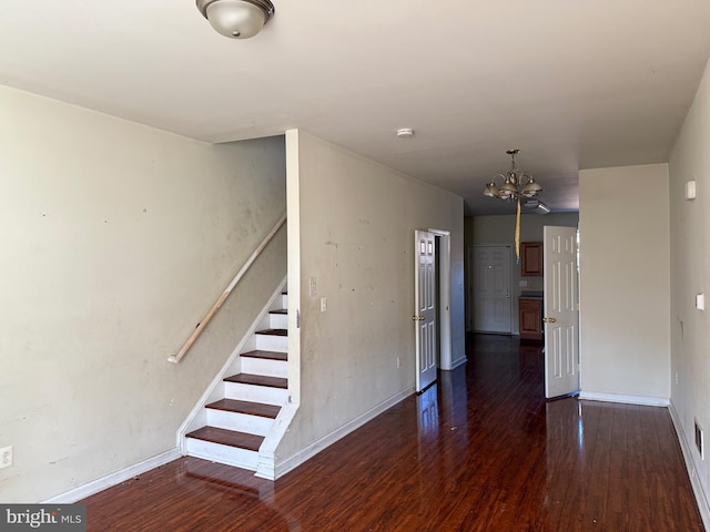 interior space featuring wood finished floors, baseboards, visible vents, an inviting chandelier, and stairs