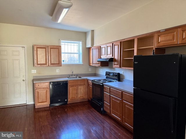 kitchen with a sink, under cabinet range hood, light countertops, black appliances, and dark wood-style flooring