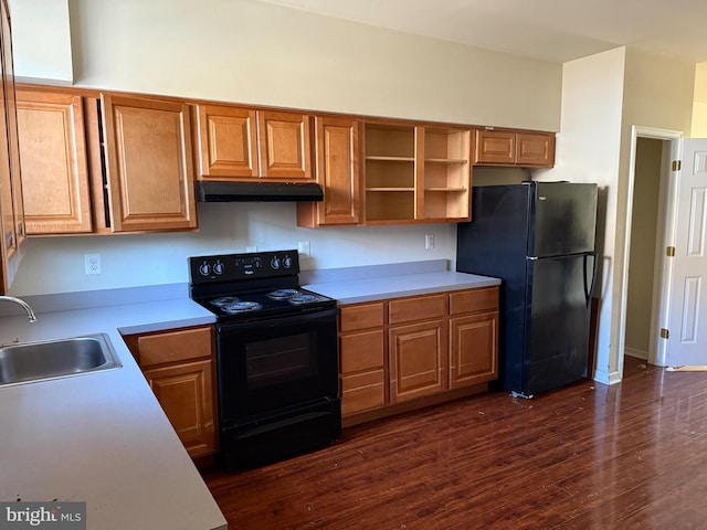 kitchen featuring under cabinet range hood, dark wood finished floors, light countertops, black appliances, and a sink