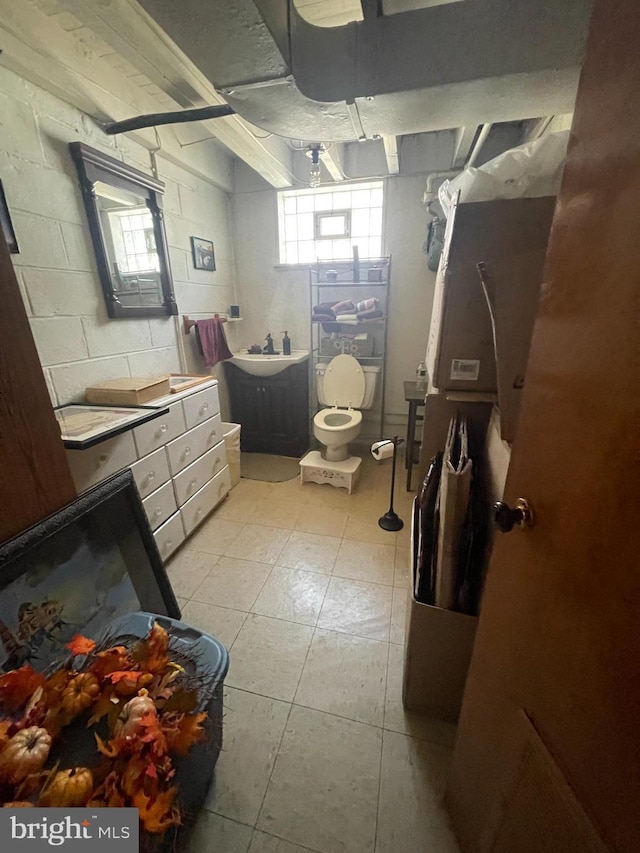 bathroom featuring concrete block wall, vanity, and toilet