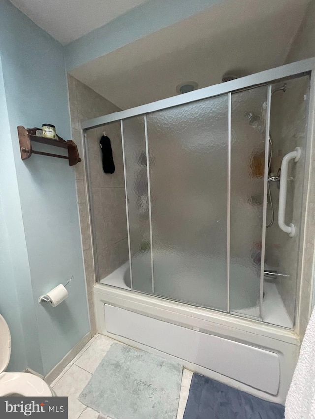 bathroom with tile patterned floors, combined bath / shower with glass door, and toilet