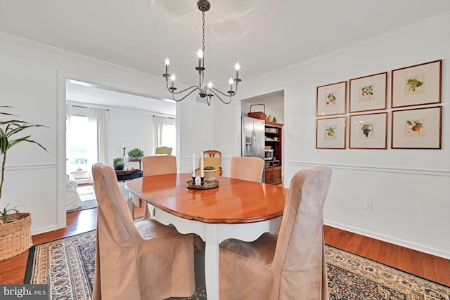 dining area featuring crown molding, wood finished floors, baseboards, and a chandelier