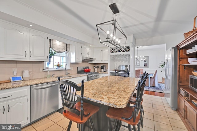 kitchen featuring light tile patterned floors, stainless steel appliances, decorative backsplash, white cabinets, and a notable chandelier