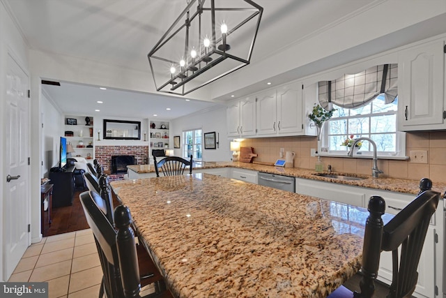 kitchen featuring a sink, light stone countertops, stainless steel dishwasher, and a fireplace