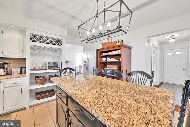 kitchen featuring tasteful backsplash, white cabinets, stainless steel refrigerator with ice dispenser, and ornamental molding