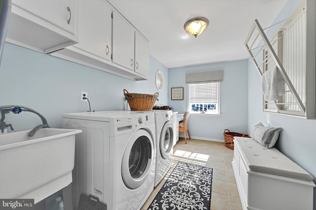 laundry room with washing machine and clothes dryer, light tile patterned floors, cabinet space, and a sink