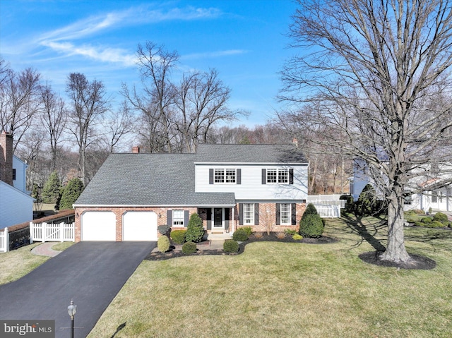 view of front facade with aphalt driveway, fence, a front yard, a garage, and brick siding