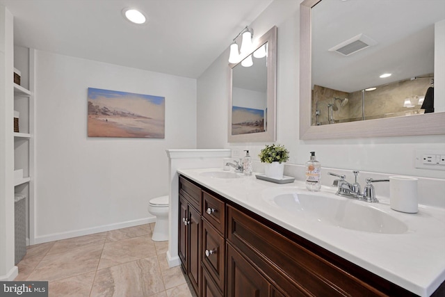 bathroom with toilet, tiled shower, visible vents, and a sink