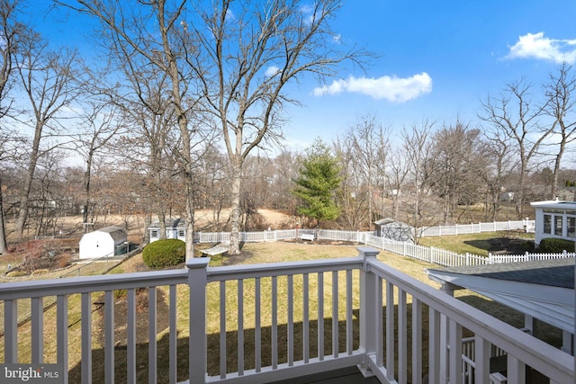 deck with a fenced backyard, a storage unit, an outdoor structure, and a yard