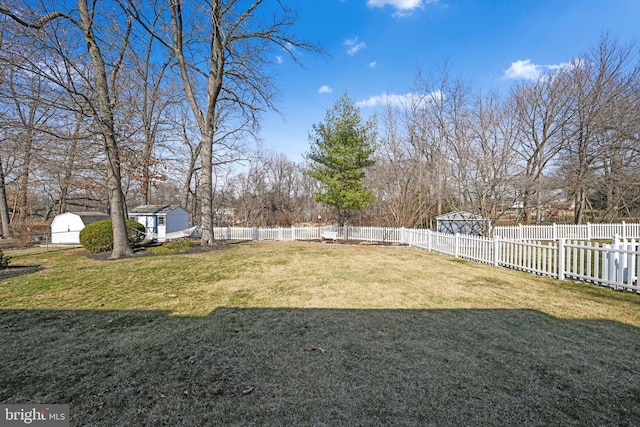 view of yard featuring a storage unit, a fenced backyard, and an outdoor structure