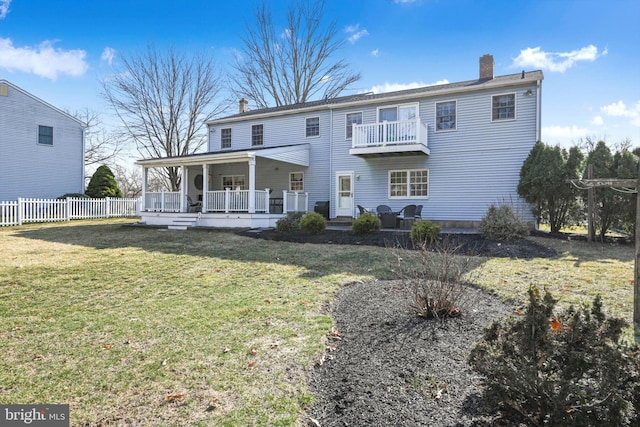 back of property featuring fence, covered porch, a lawn, a chimney, and a balcony