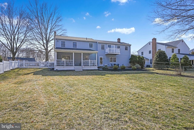 back of house featuring a lawn, covered porch, a fenced backyard, and a chimney