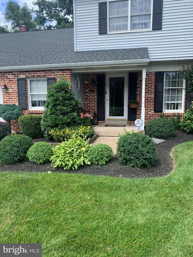 property entrance with brick siding and a shingled roof