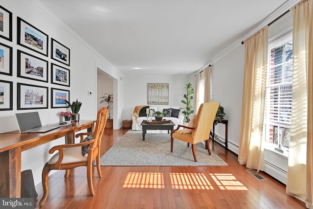 office with baseboard heating, ornamental molding, visible vents, and wood-type flooring