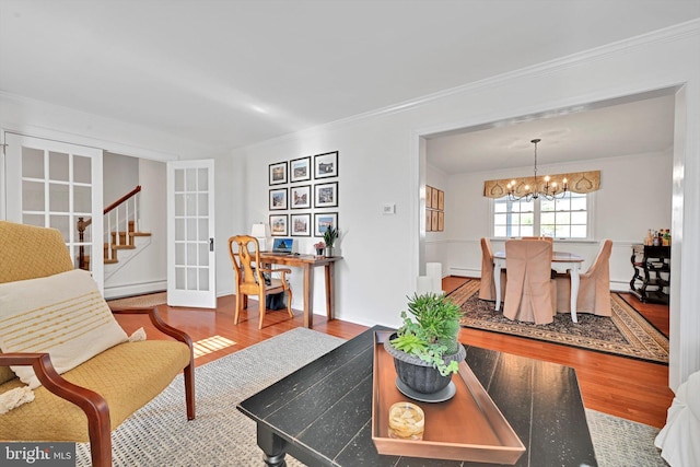 living room with ornamental molding, a baseboard heating unit, an inviting chandelier, and wood finished floors