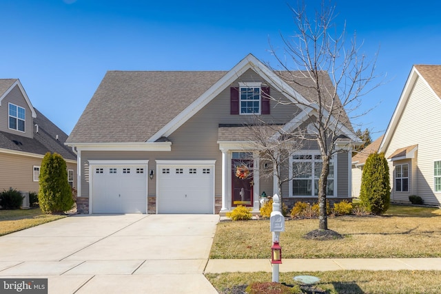 view of front of home with roof with shingles, an attached garage, concrete driveway, a front lawn, and stone siding