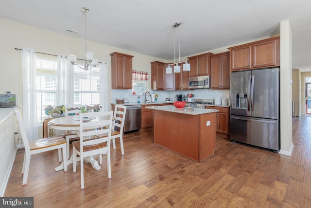 kitchen with a sink, wood finished floors, brown cabinets, and stainless steel appliances