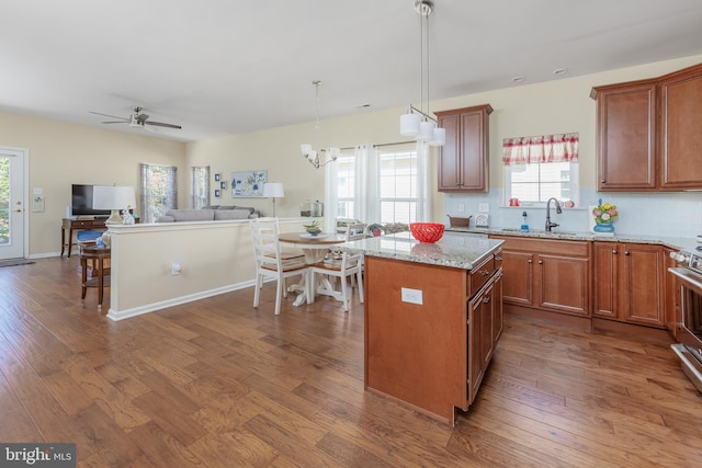 kitchen featuring dark wood finished floors, backsplash, a kitchen island, and a sink