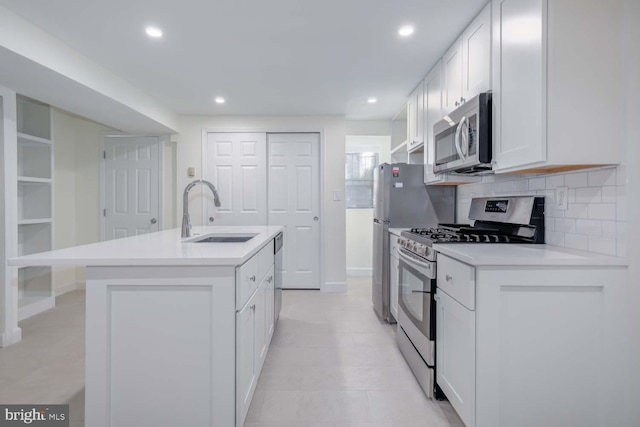 kitchen with an island with sink, a sink, tasteful backsplash, white cabinetry, and stainless steel appliances