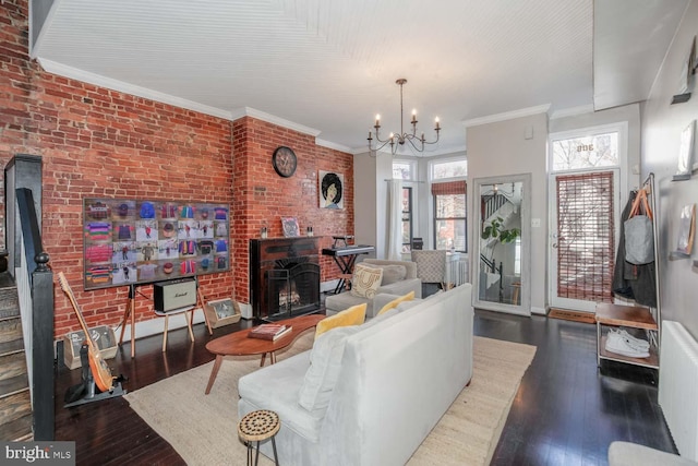 living area featuring hardwood / wood-style floors, an inviting chandelier, brick wall, and ornamental molding