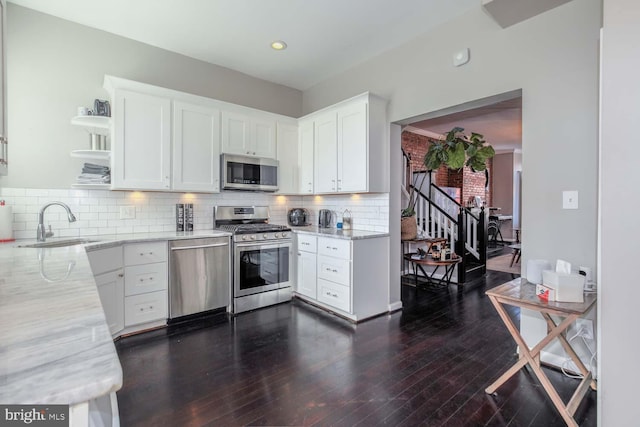 kitchen featuring a sink, open shelves, stainless steel appliances, white cabinets, and light stone countertops