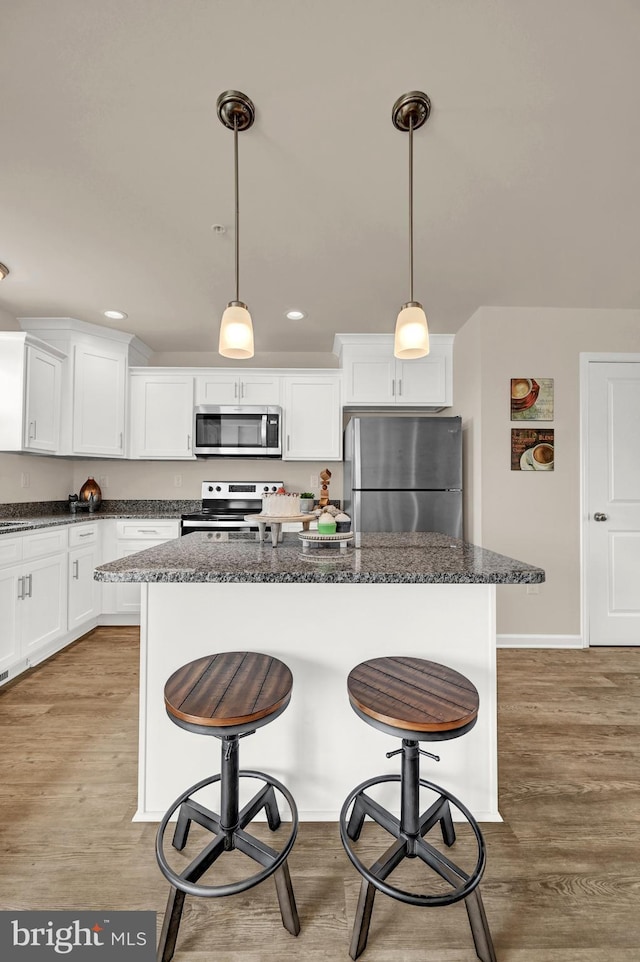 kitchen with a breakfast bar, light wood finished floors, and appliances with stainless steel finishes