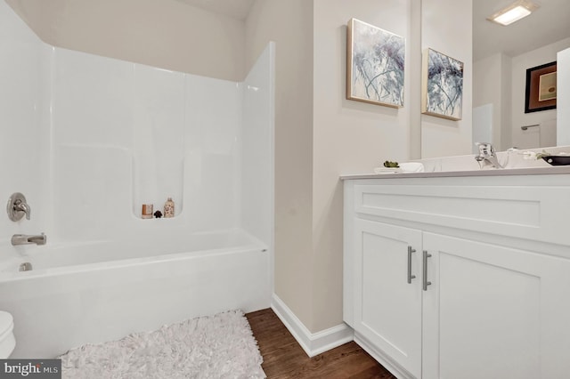 full bathroom with baseboards, vanity, wood finished floors, and washtub / shower combination