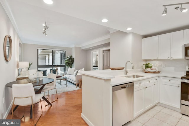 kitchen with ornamental molding, a sink, open floor plan, stainless steel appliances, and decorative backsplash