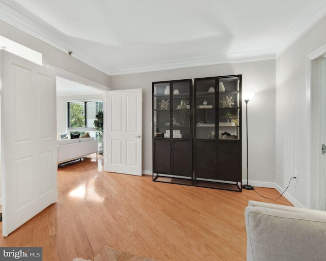 interior space featuring baseboards, light wood-style flooring, and crown molding