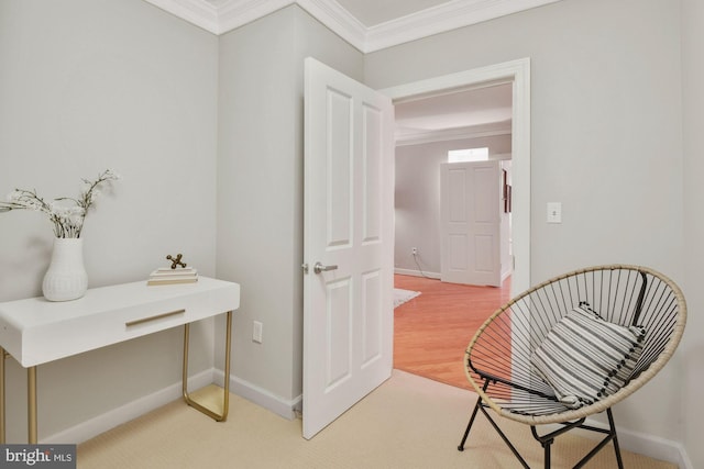 sitting room with baseboards, light wood-style flooring, and crown molding