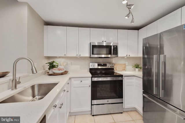 kitchen with tasteful backsplash, light countertops, light tile patterned floors, appliances with stainless steel finishes, and a sink