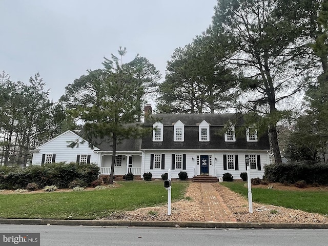 view of front of home featuring a chimney, a shingled roof, and a front yard