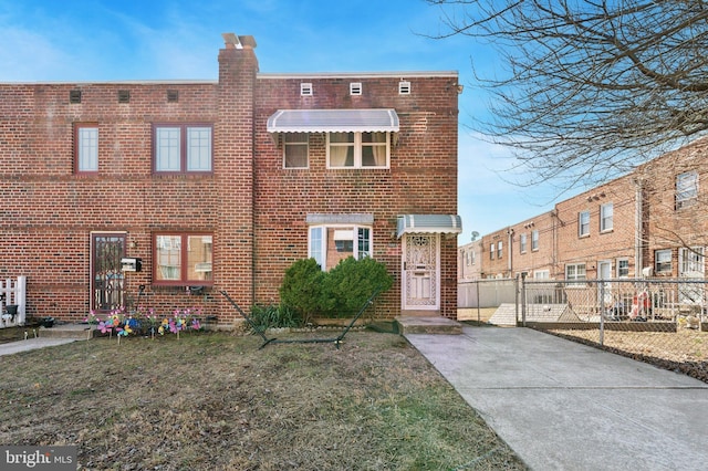 view of front of house with a front lawn, fence, brick siding, and a chimney