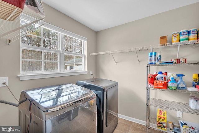 laundry room with tile patterned floors, baseboards, separate washer and dryer, and laundry area