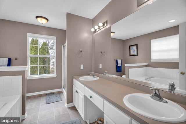 full bathroom with a garden tub, double vanity, baseboards, and a sink