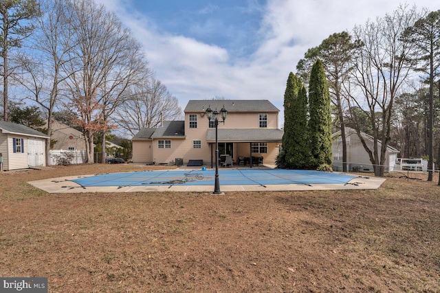 rear view of property featuring a fenced in pool, fence, a yard, and a patio area