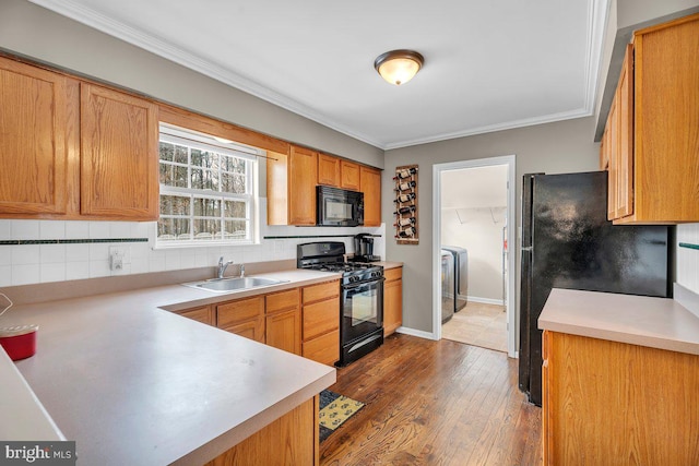 kitchen featuring black appliances, a sink, tasteful backsplash, crown molding, and light countertops