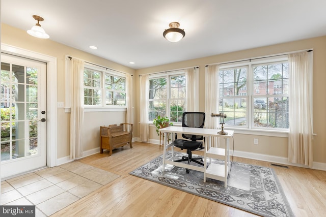 home office with a wealth of natural light, visible vents, baseboards, and wood finished floors