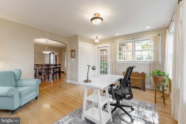 home office featuring arched walkways, recessed lighting, light wood-style flooring, and baseboards