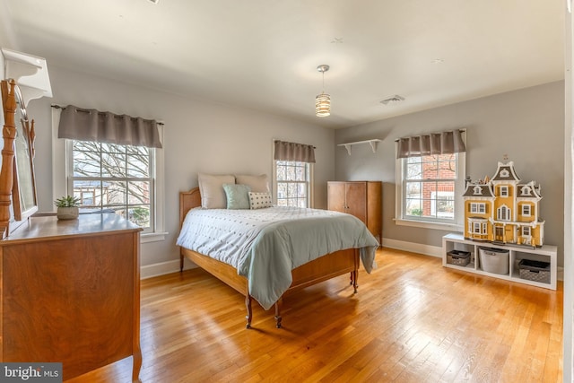 bedroom featuring multiple windows, baseboards, and hardwood / wood-style floors