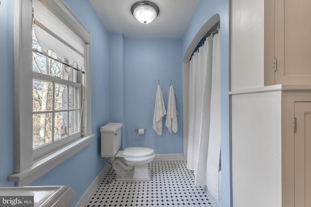 full bath featuring a shower with shower curtain, baseboards, toilet, and tile patterned floors