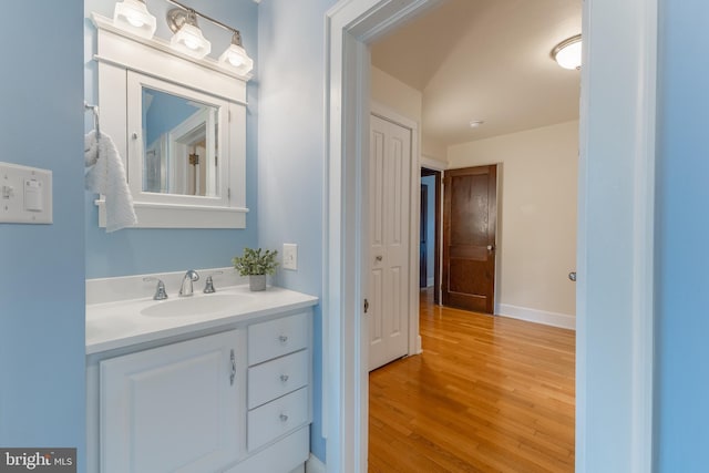 bathroom with vanity, wood finished floors, and baseboards