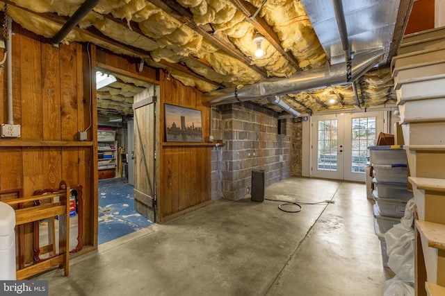 basement featuring french doors and concrete block wall