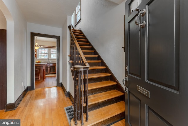 stairs featuring arched walkways, visible vents, baseboards, and hardwood / wood-style flooring