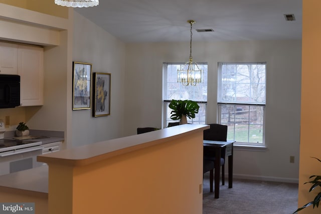 kitchen featuring visible vents, light carpet, white cabinetry, black microwave, and a chandelier